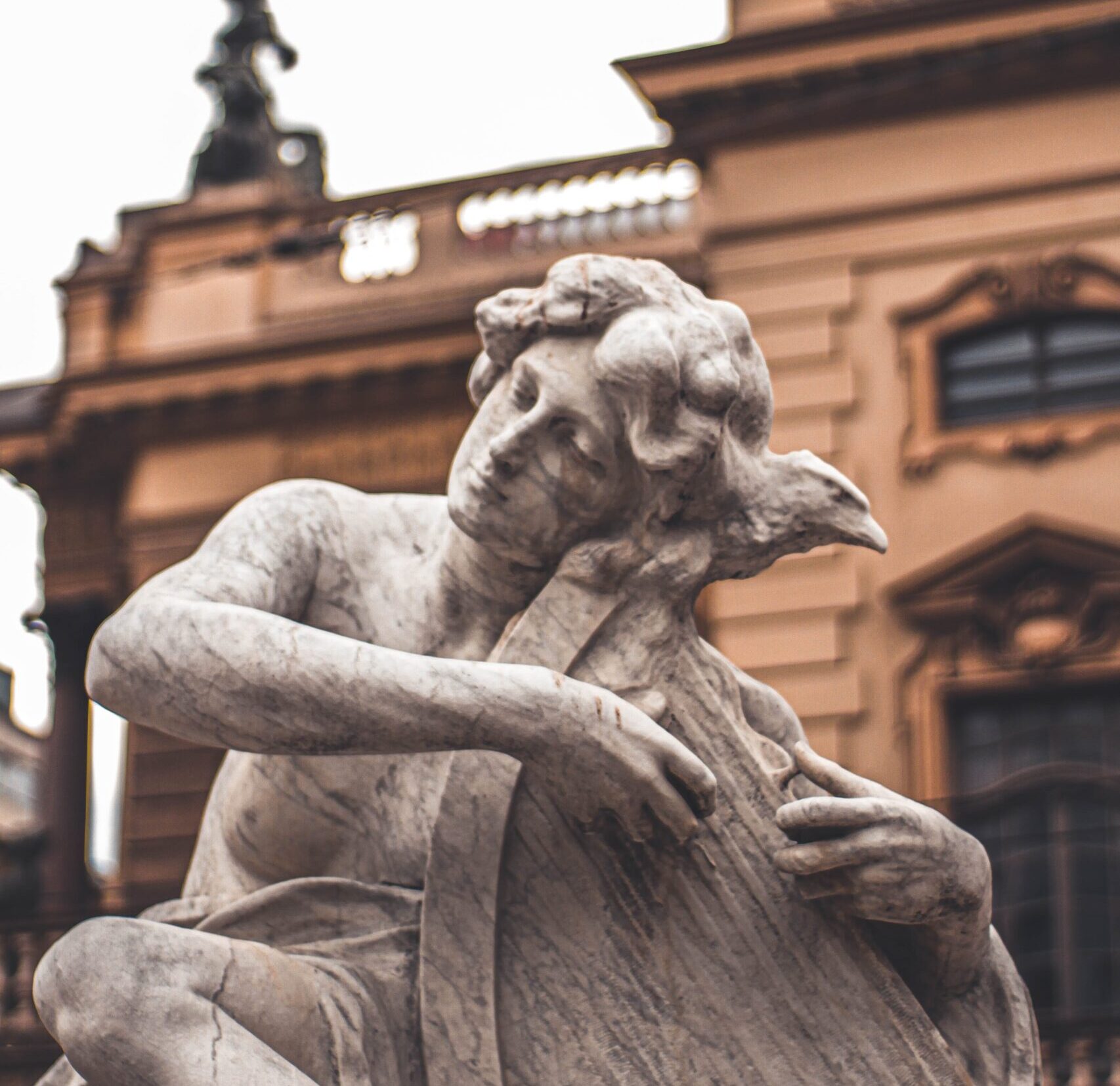 A stone carving of an angel or person playing the harp, with an eagle on their shoulder.