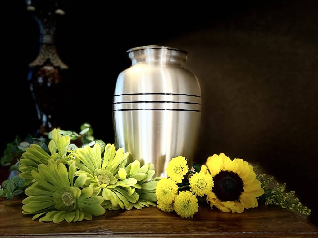 A cremation jar surrounded by beautiful flowers.